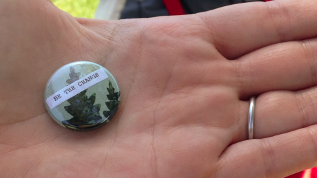 Hand holding badge which reads ''be the change' courtesy of Santa Cruz Museum of Art and History